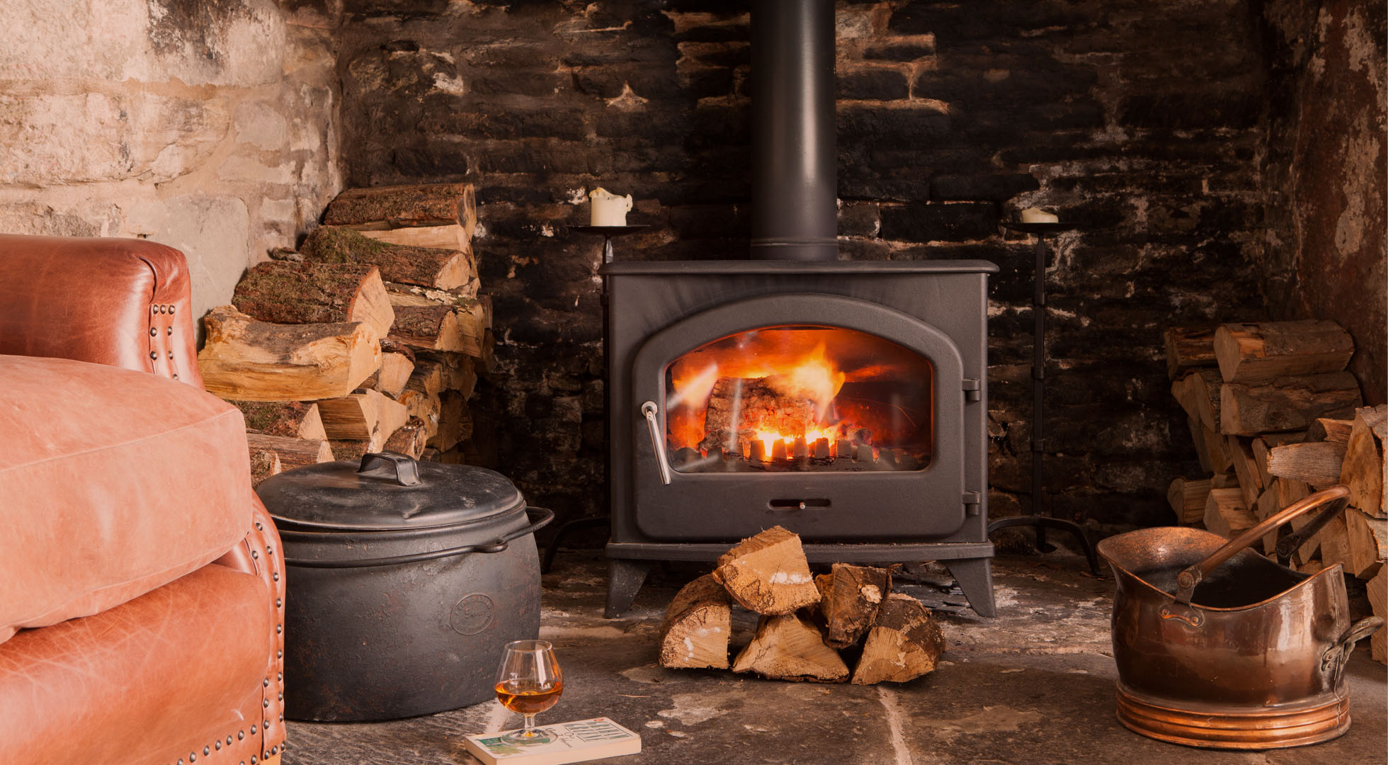 front page image of a log fire with a sofa and brandy resting on a book, for Tudor Farmhouse Hotel, Christmas 2019