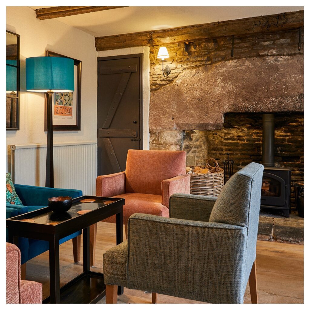Lounge at the Tudor Farmhouse showing chairs and the large fireplace.